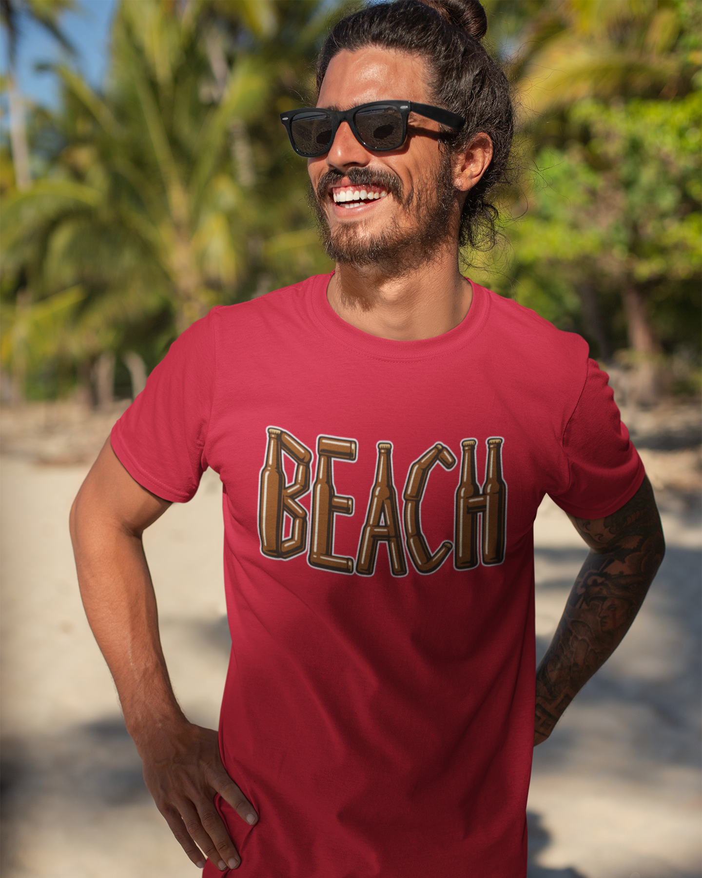 Man wearing a red 'BEACH' t-shirt on a beach with palm trees in the background