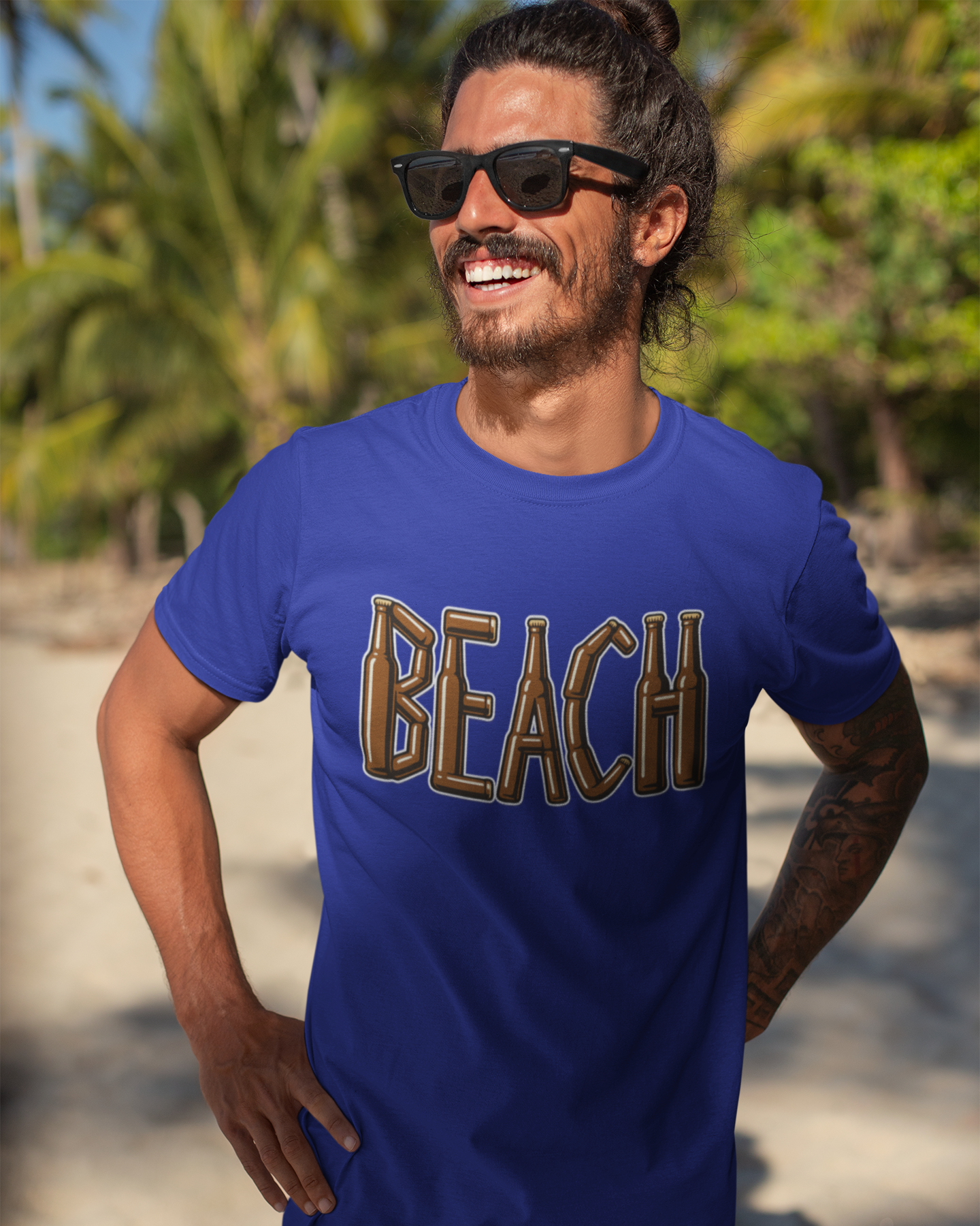 Man wearing a blue 'BEACH' t-shirt on a beach with palm trees in the background