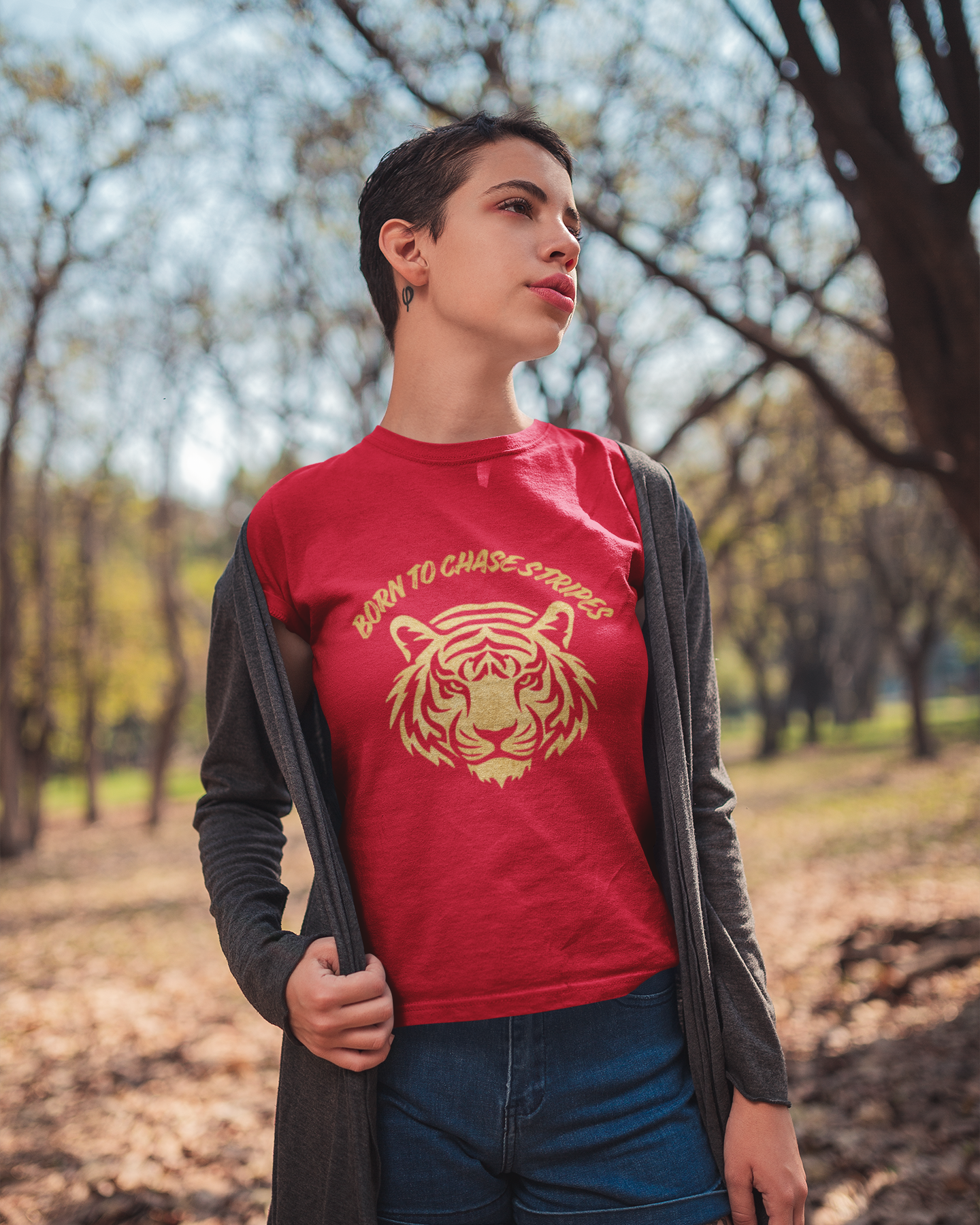 Person wearing a red t-shirt with a tiger graphic and text, standing outdoors in a park.