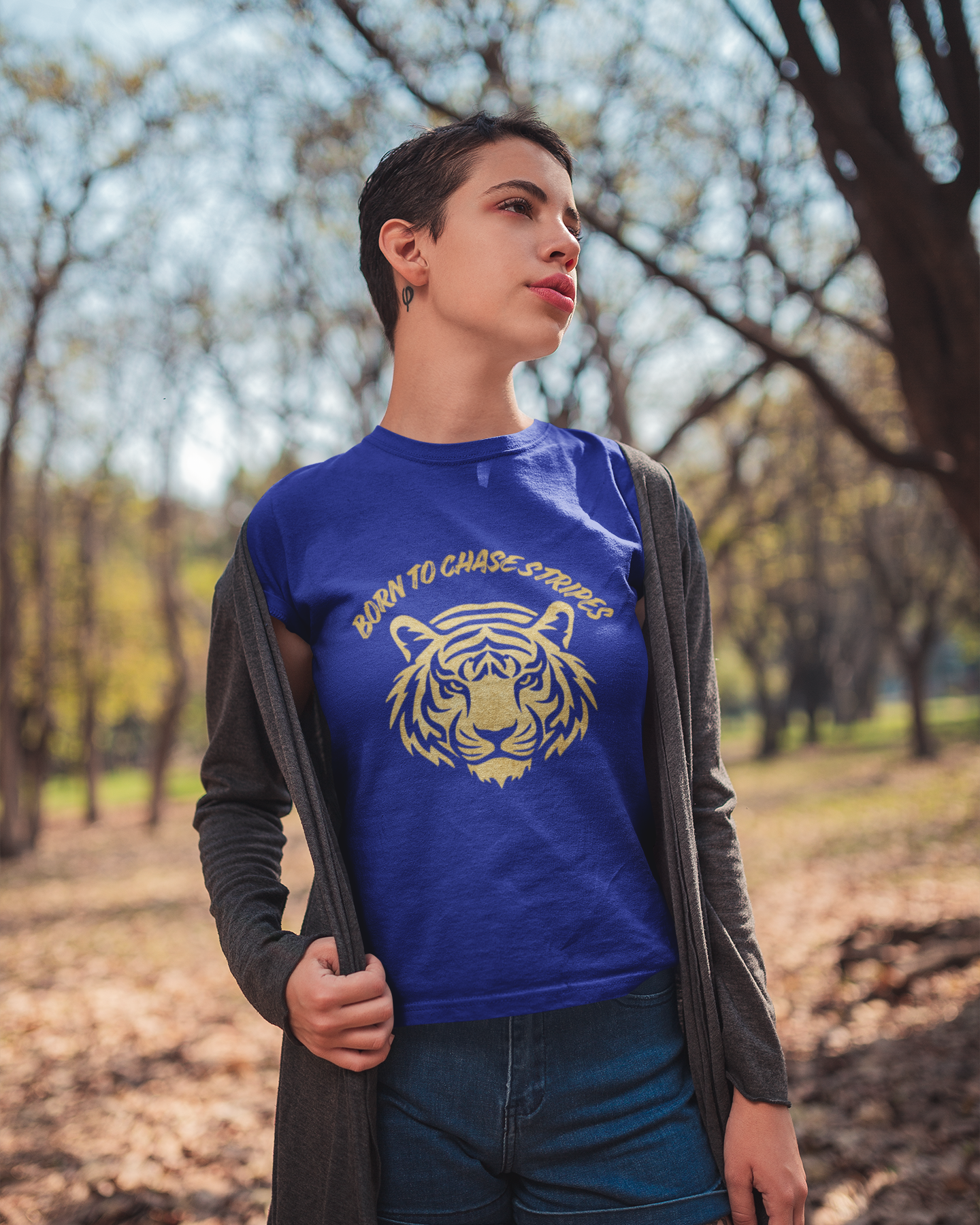 Person wearing a blue t-shirt with a tiger graphic and text, standing outdoors in a park.