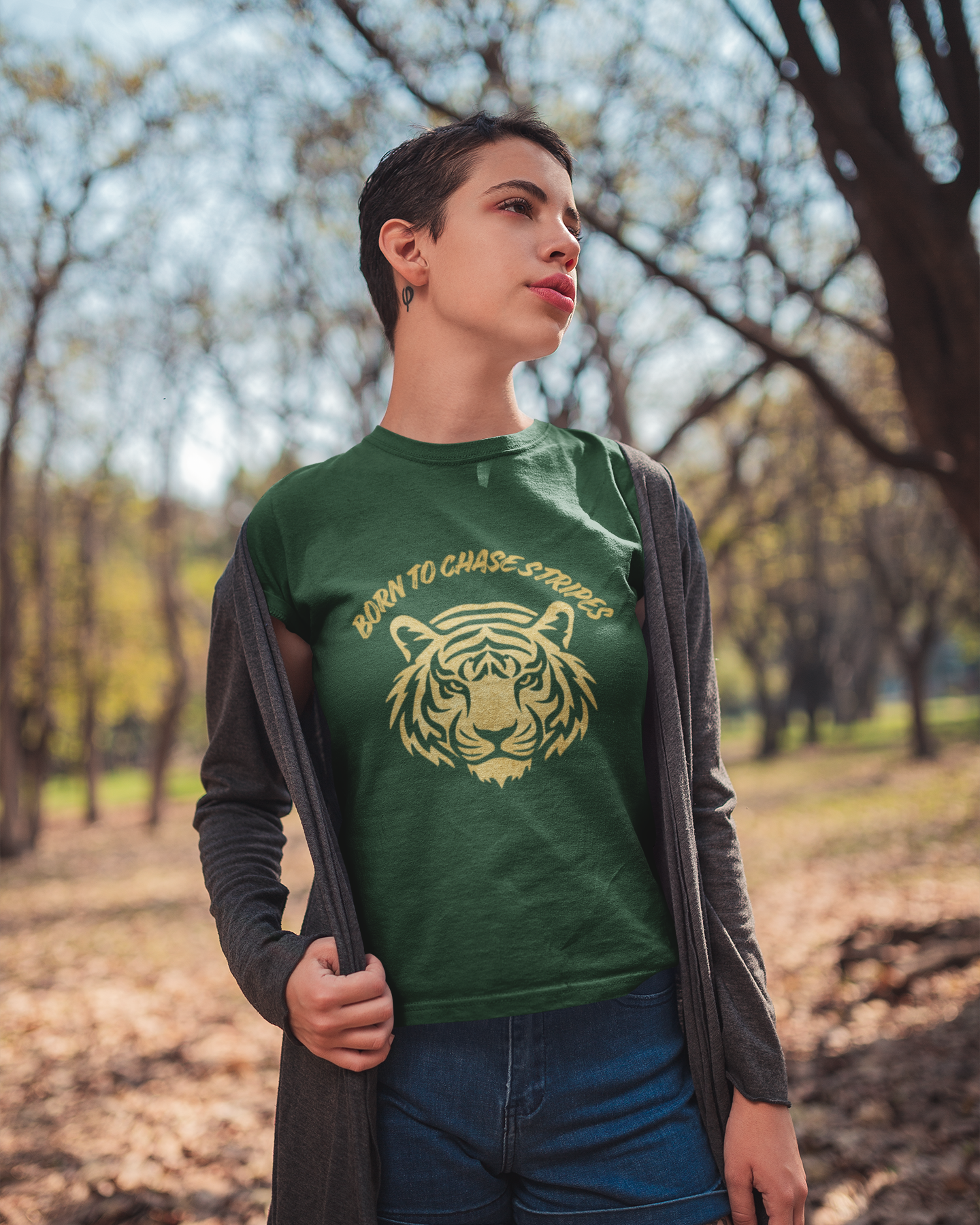 Person wearing a green t-shirt with a tiger graphic and text, standing outdoors in a park.