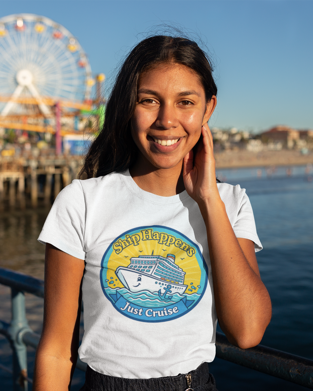Woman wearing a t-shirt with a graphic design by the water, with a Ferris wheel in the background.