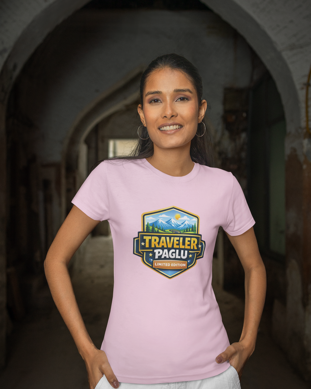 Woman wearing a pink t-shirt with a 'Traveler Paglu' logo in an arched doorway.