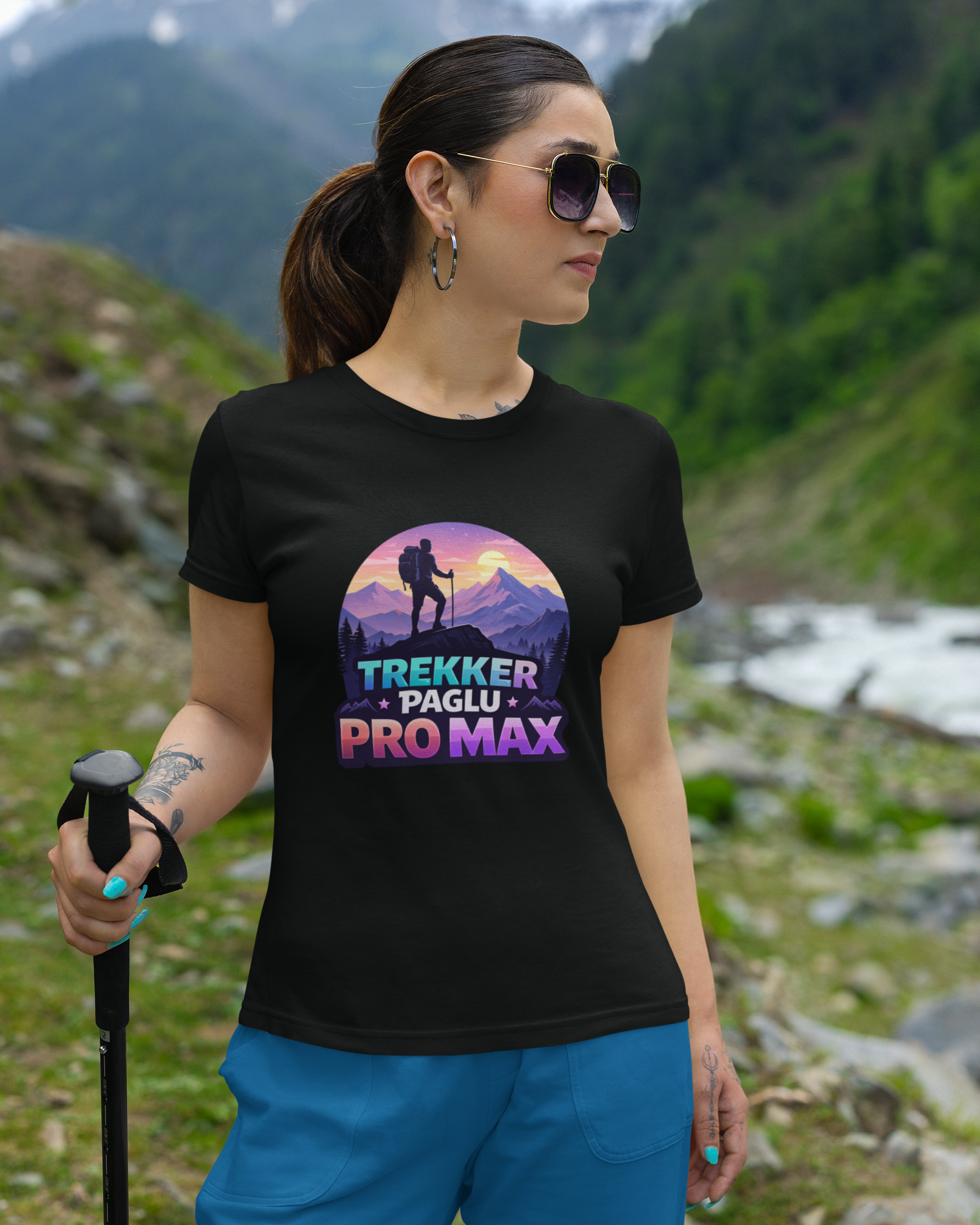 Person wearing a black t-shirt with a colorful graphic and text, standing in a mountainous landscape.