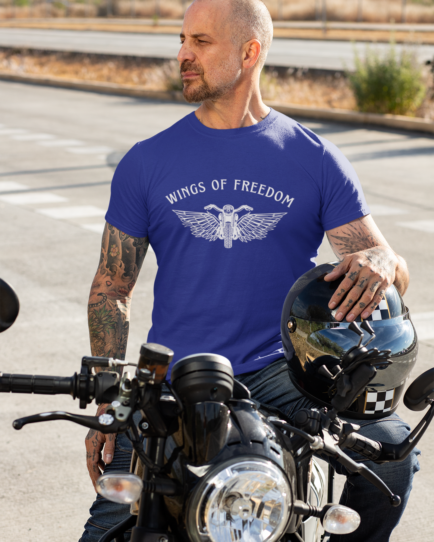 Man wearing a blue 'Wings of Freedom' t-shirt on a motorcycle.