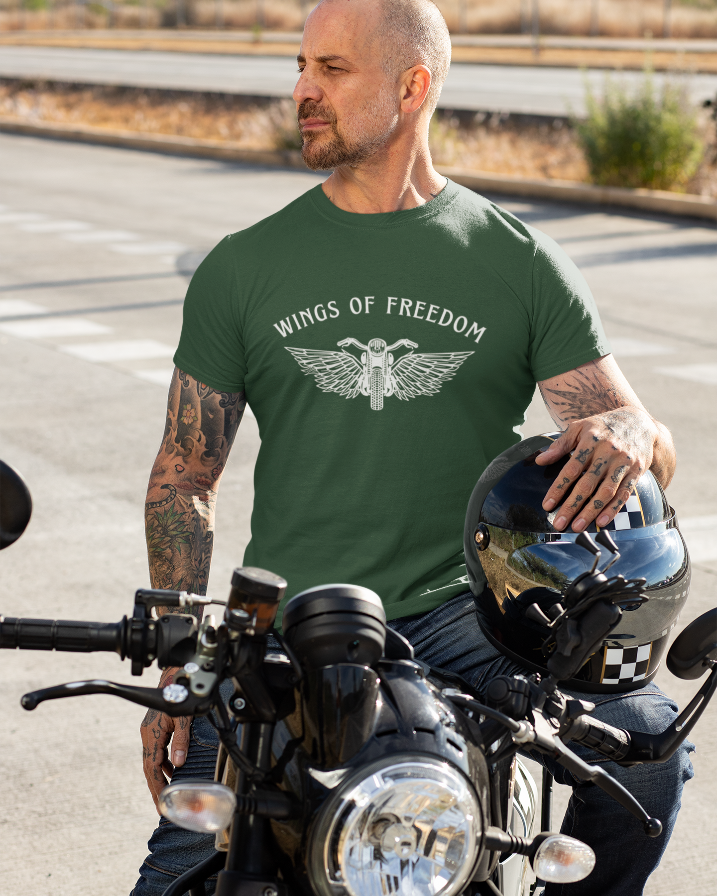 Man wearing a green 'Wings of Freedom' t-shirt while sitting on a motorcycle.