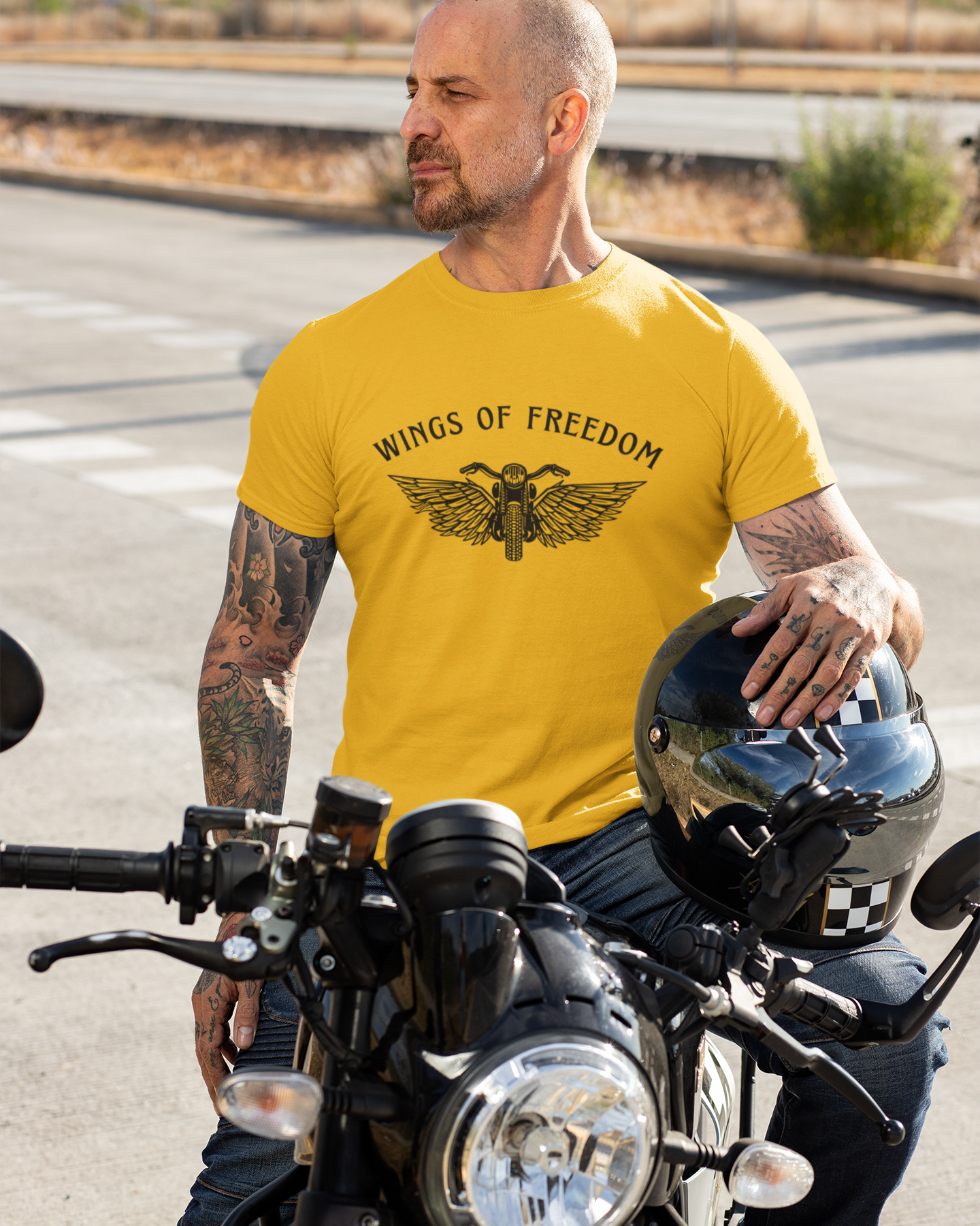 Man wearing a yellow 'Wings of Freedom' t-shirt on a motorcycle.