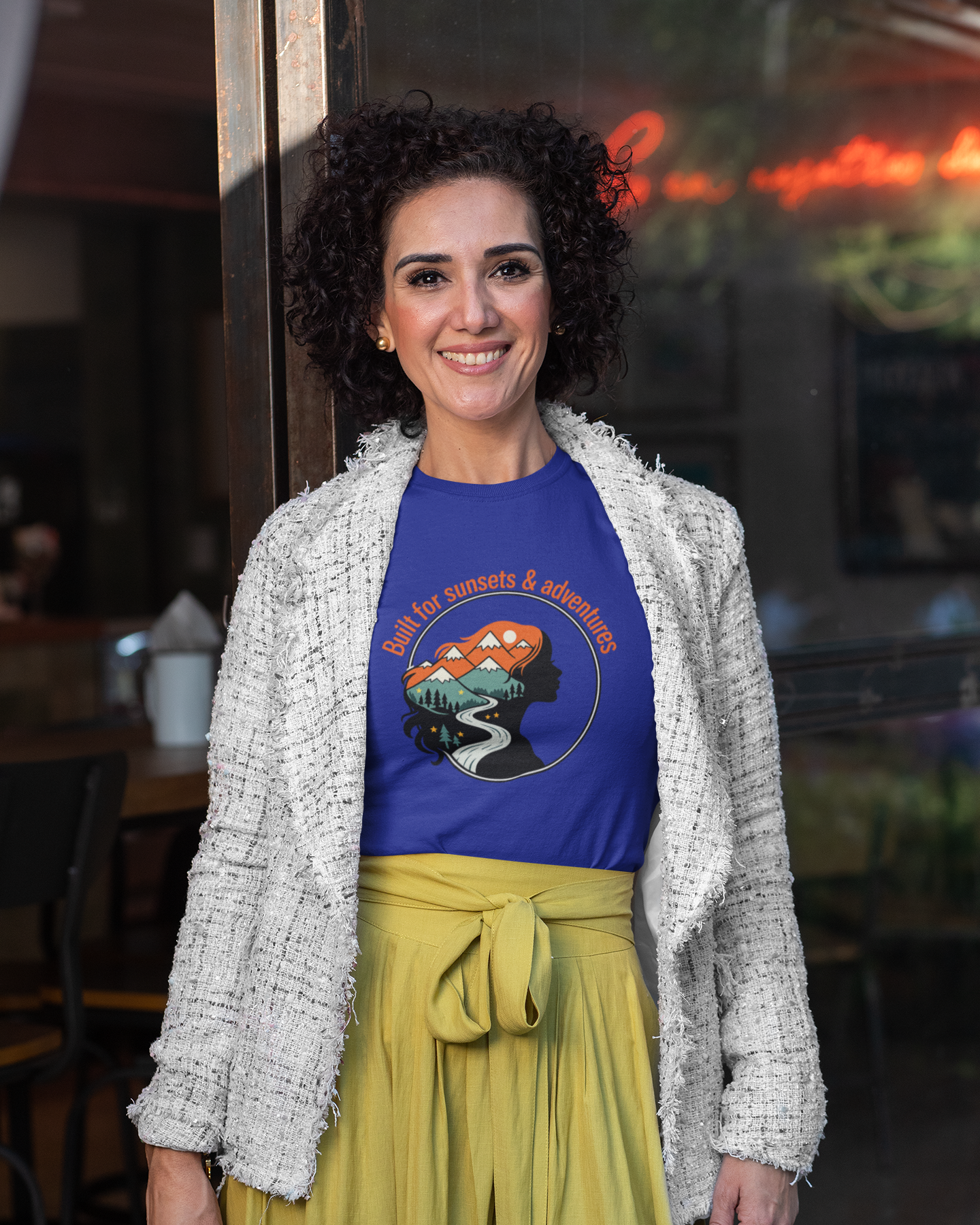 Woman wearing a blue t-shirt with a graphic design and yellow pants in an indoor setting.