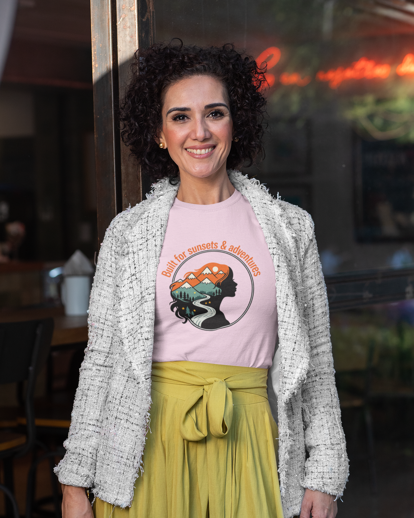 Woman wearing a pink t-shirt with a graphic design and a yellow skirt in an indoor setting.