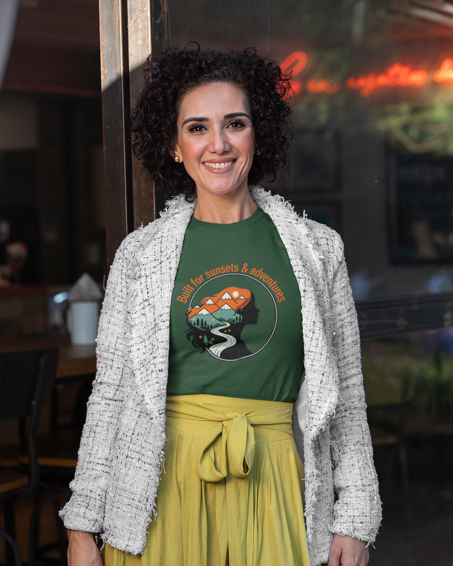 Woman wearing a green t-shirt with a graphic design and yellow pants in an indoor setting.
