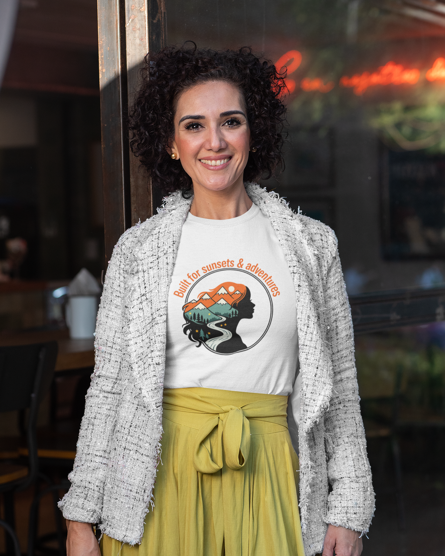 Woman wearing a white t-shirt with a graphic design and a yellow skirt in an indoor setting.