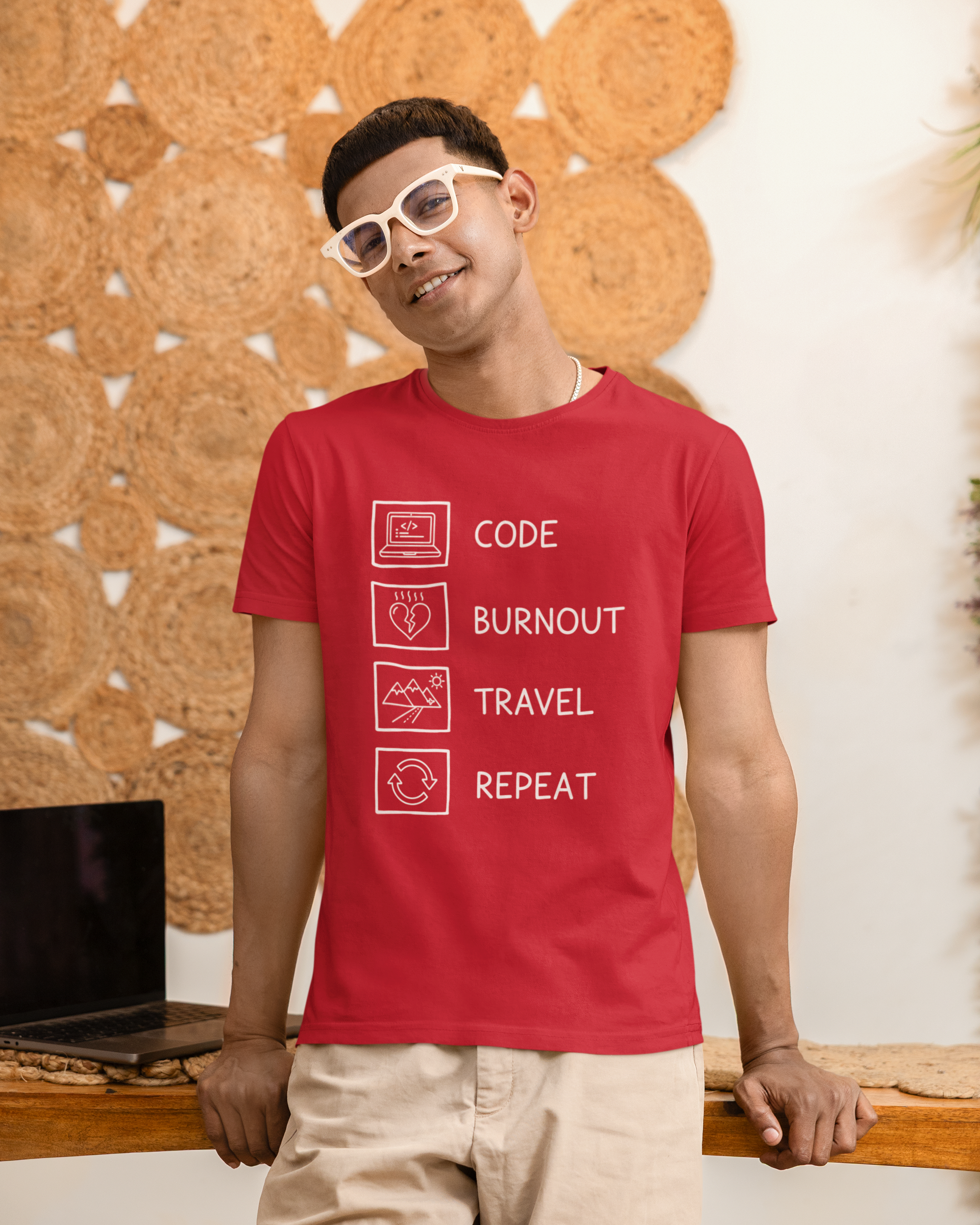 Man wearing a red t-shirt with text design, standing against a textured wall.