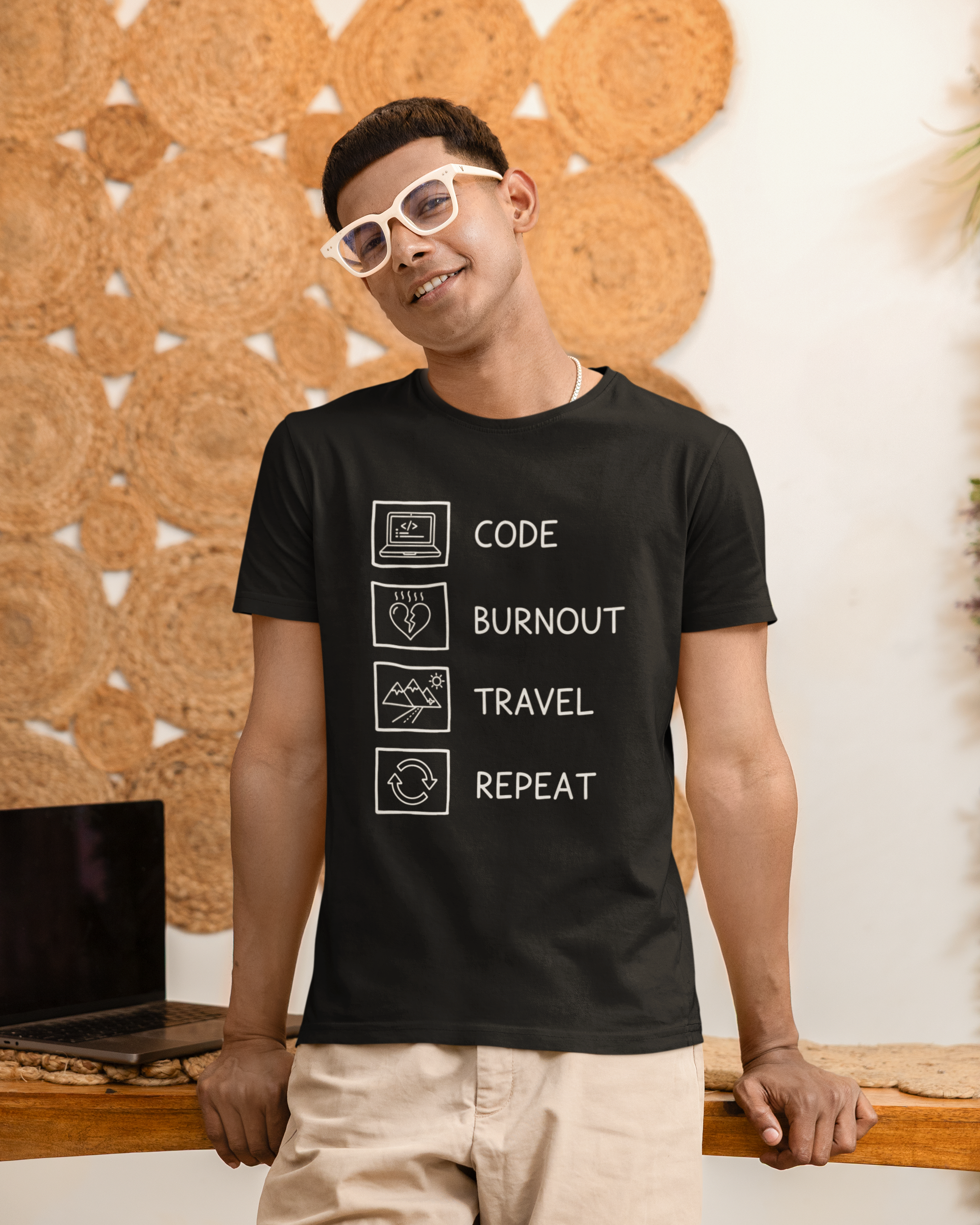 Man wearing a black t-shirt with text design, standing against a textured wall.