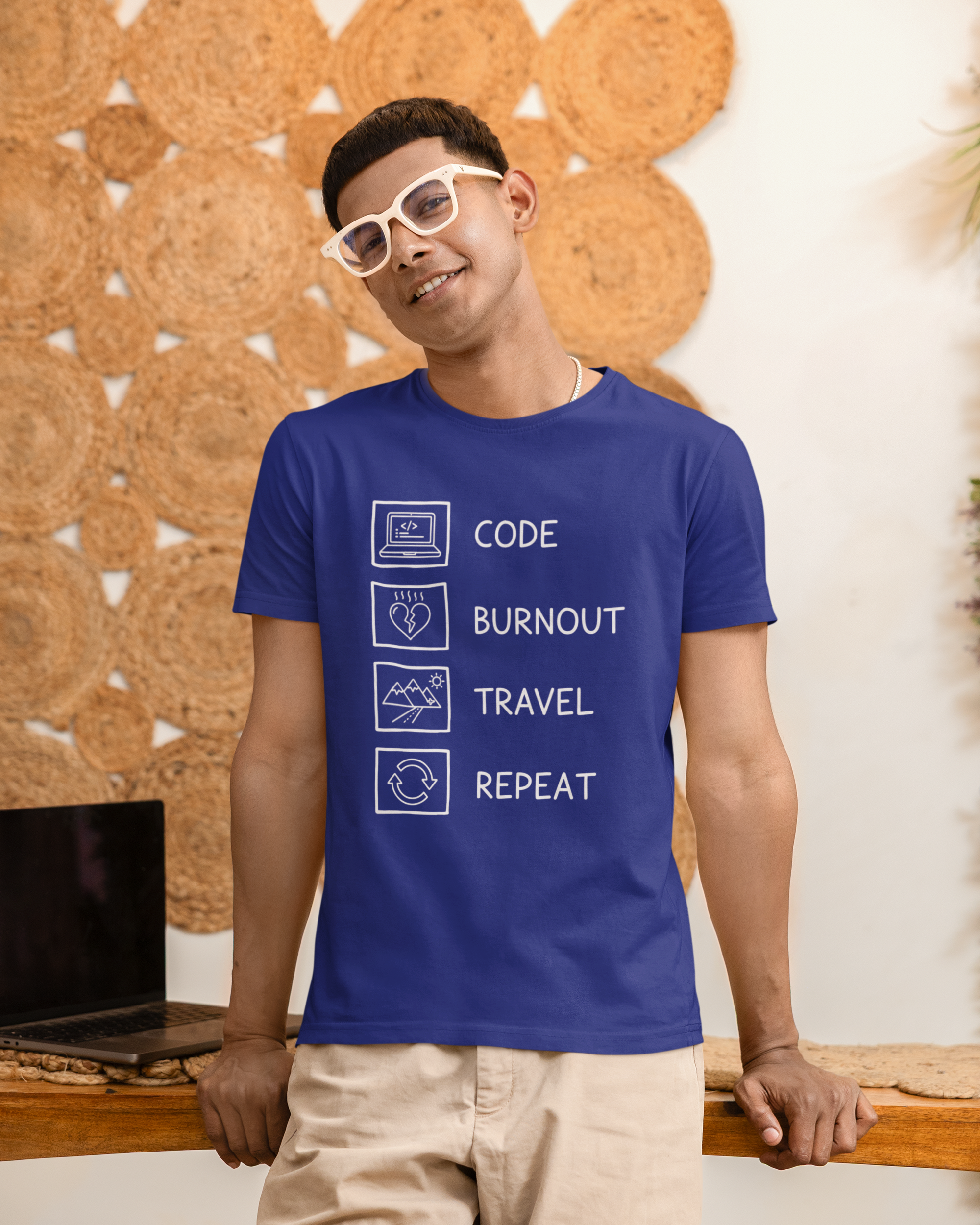 Man wearing a blue t-shirt with text design, standing against a textured wall.