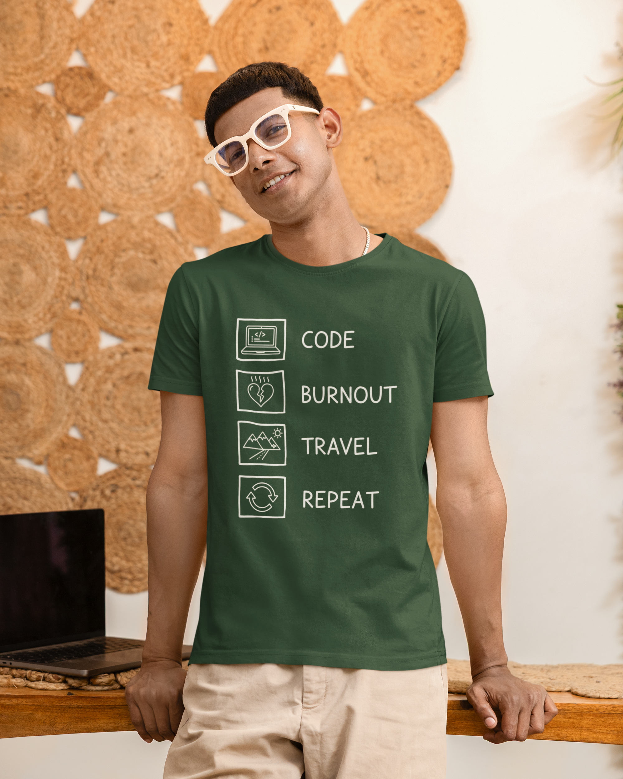 Man wearing a green t-shirt with text design, standing against a textured wall.