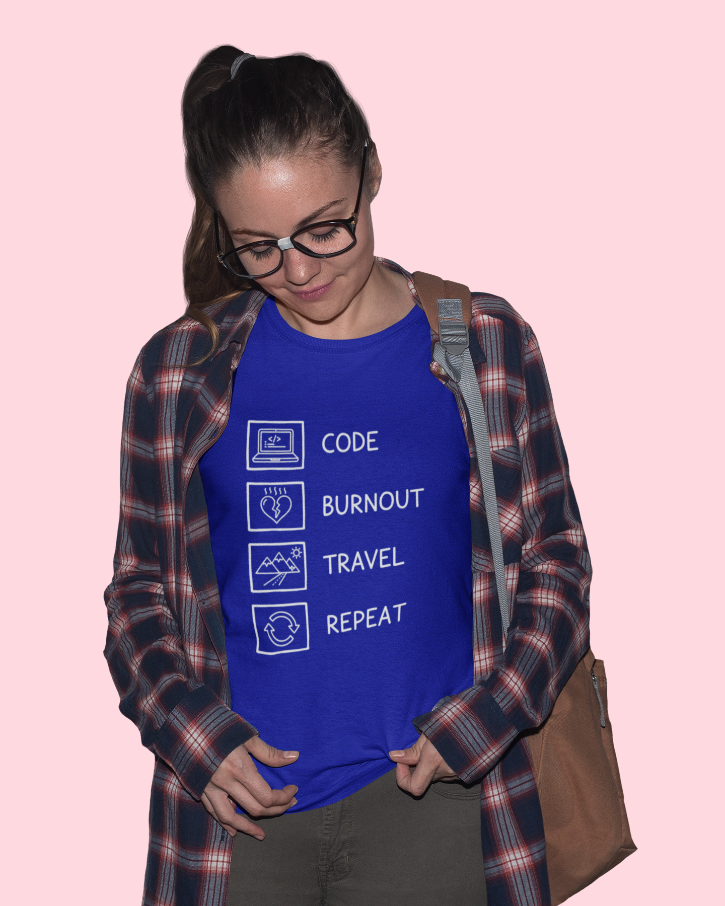 Person wearing a blue t-shirt with text and symbols, standing against a pink background