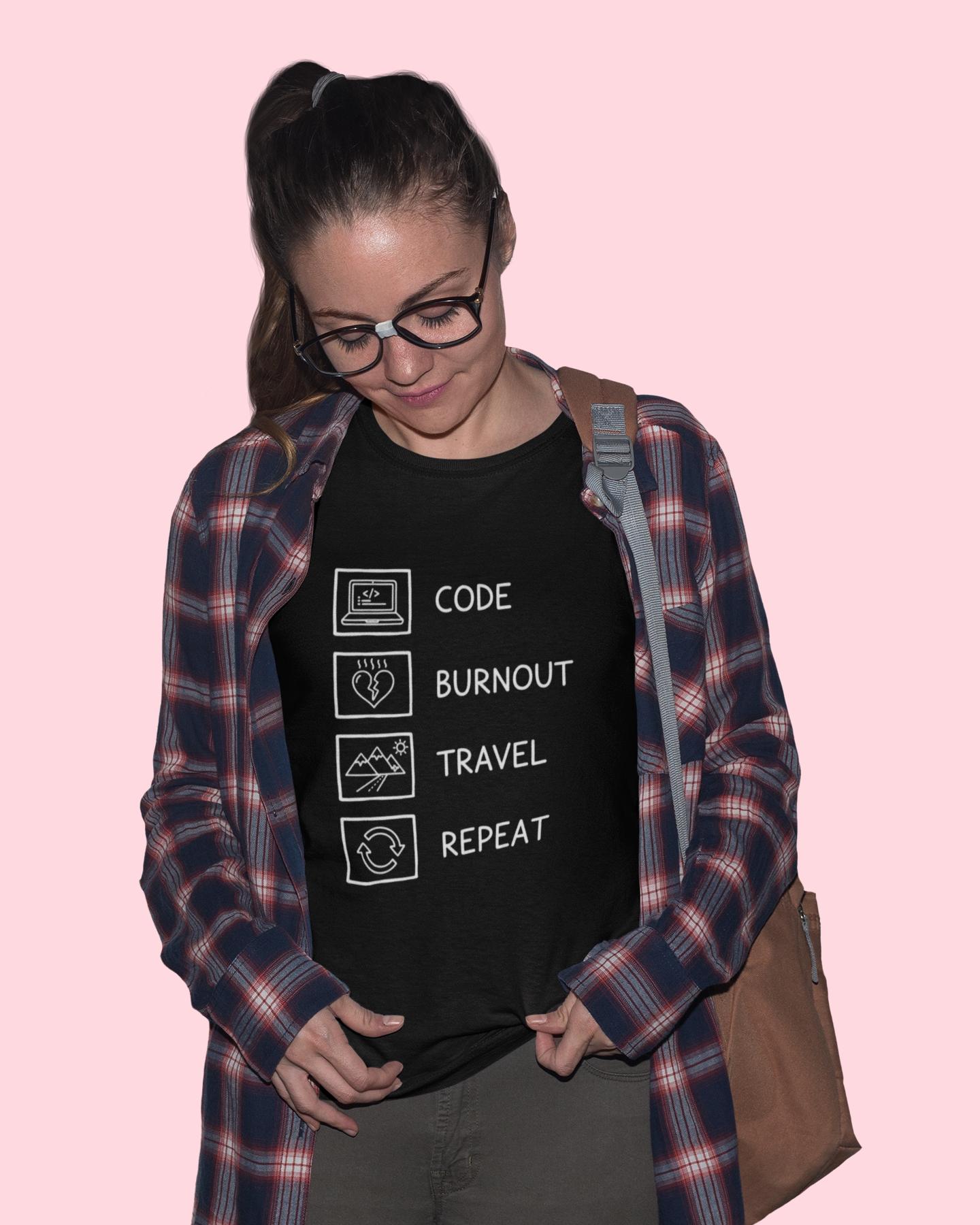 Person wearing a black t-shirt with text and symbols, standing against a pink background