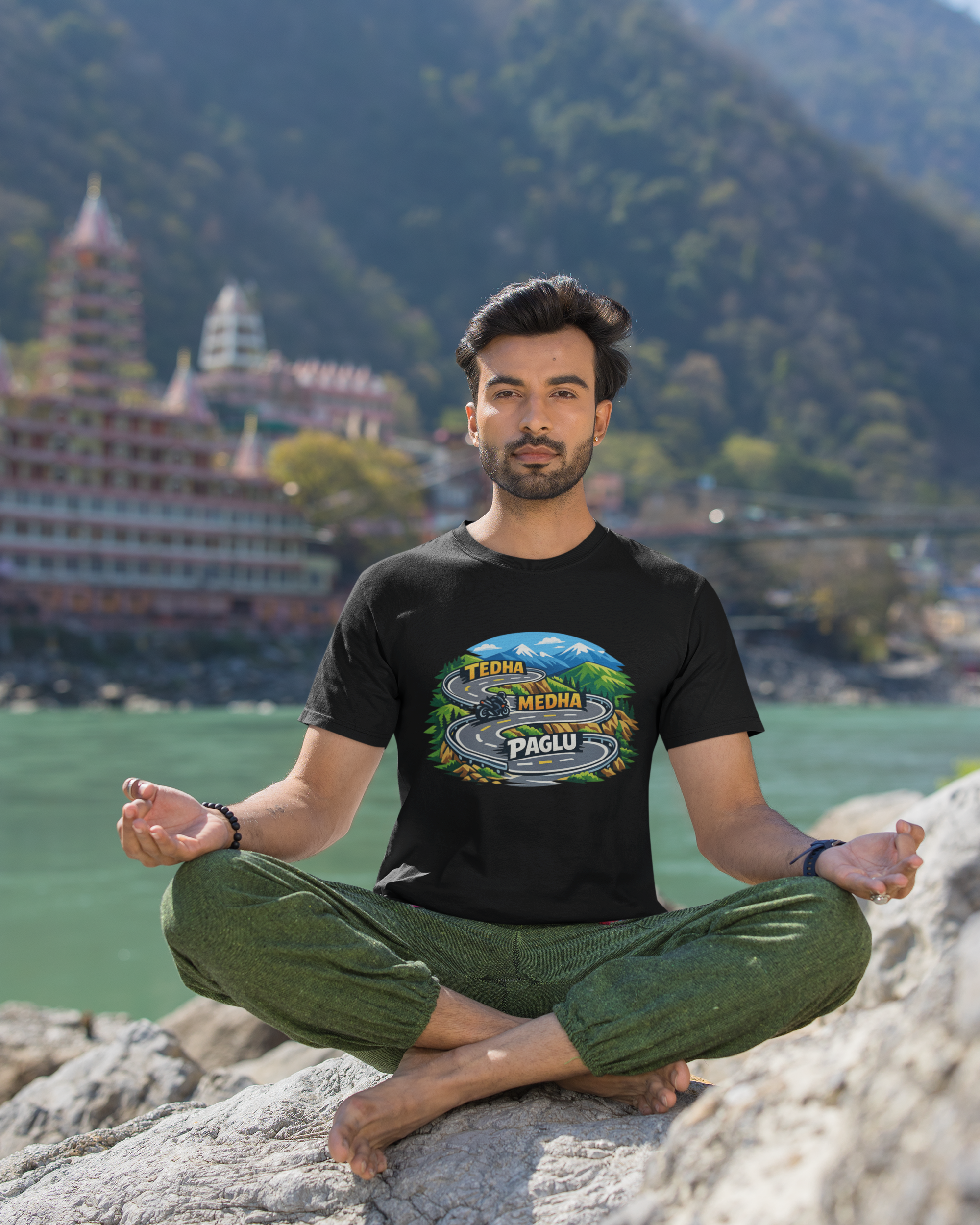 Man meditating on a rock with a scenic background of mountains and a temple.