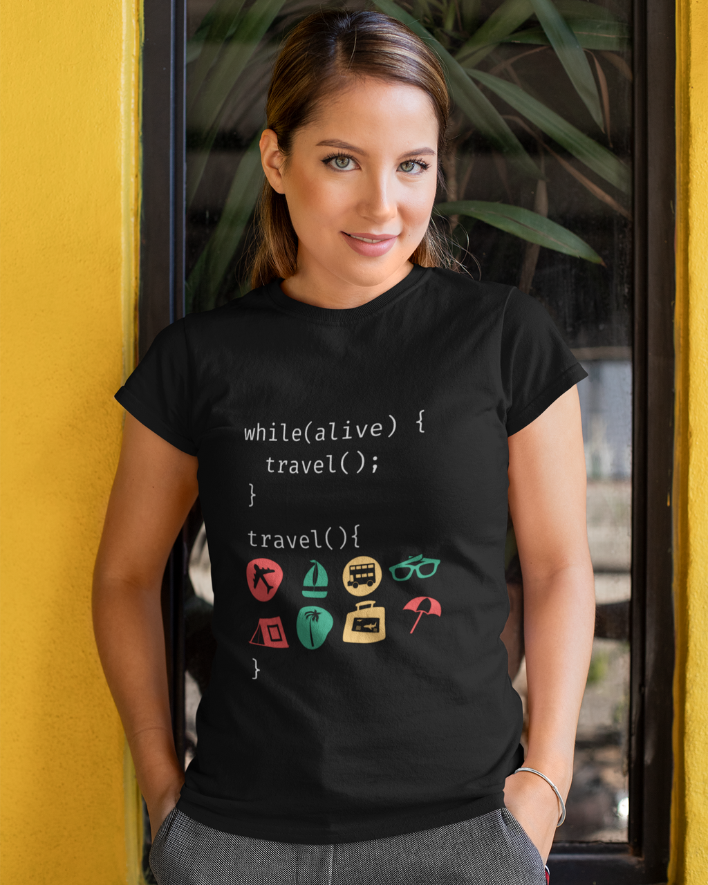 Woman wearing a black t-shirt with travel-themed code design against a yellow wall.