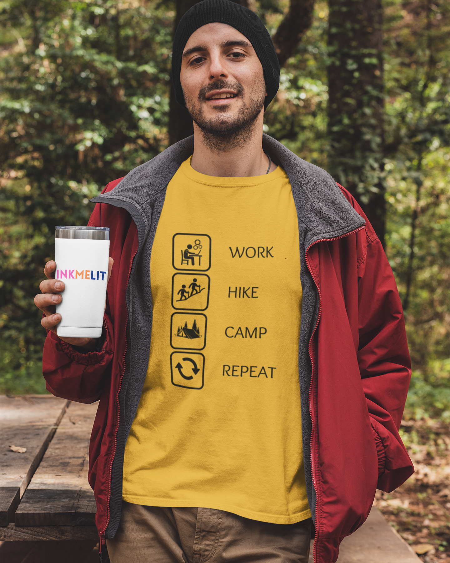 Man holding a mug with a yellow t-shirt featuring outdoor-themed graphics in a forest setting